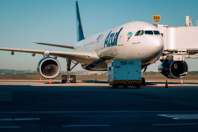Avião comercial estacionado junto ao portão de embarque de um aeroporto em um dia ensolarado