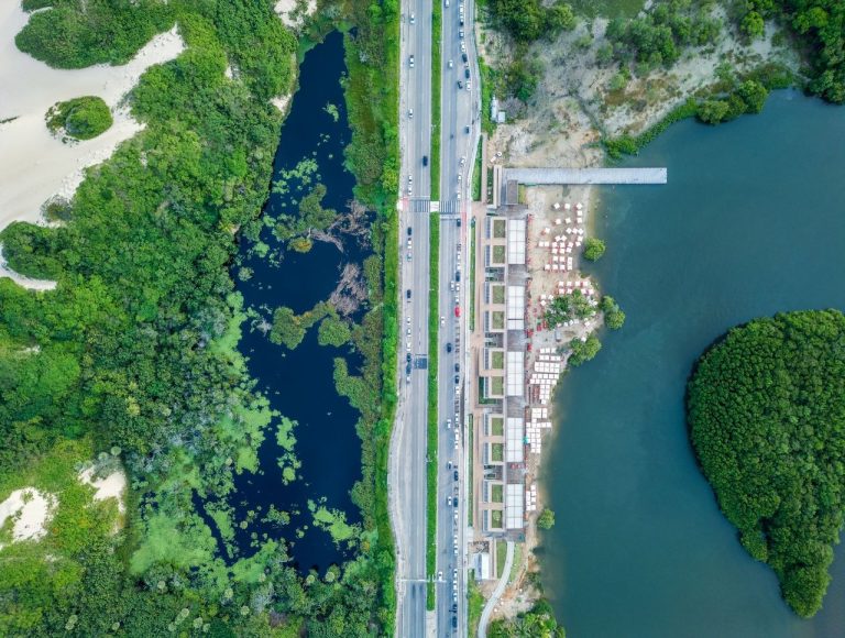 Infraestrutura básica passa a acompanhar a expansão turística no litoral do Ceará Vista aérea de trecho do litoral de Fortaleza, com faixa urbana, via costeira, áreas verdes e o oceano ao fundo.